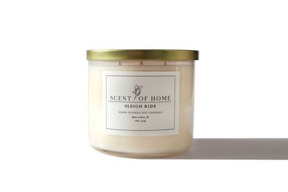 Scent of Home Sleigh Ride candle in clear glass jar with gold lid on a white background