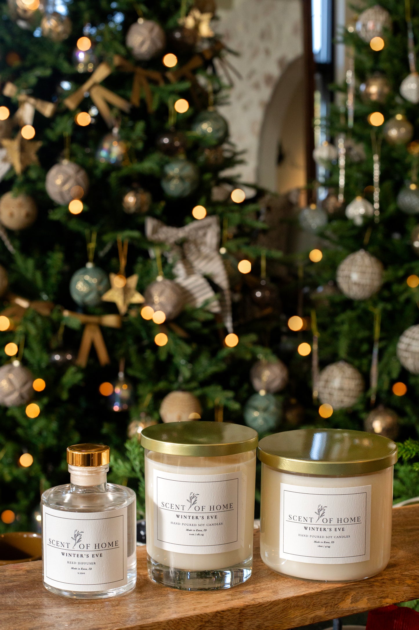 Scent of Home Winter’s Eve holiday bundle featuring a reed diffuser, classic candle, and 3-wick candle displayed in front of a decorated Christmas tree