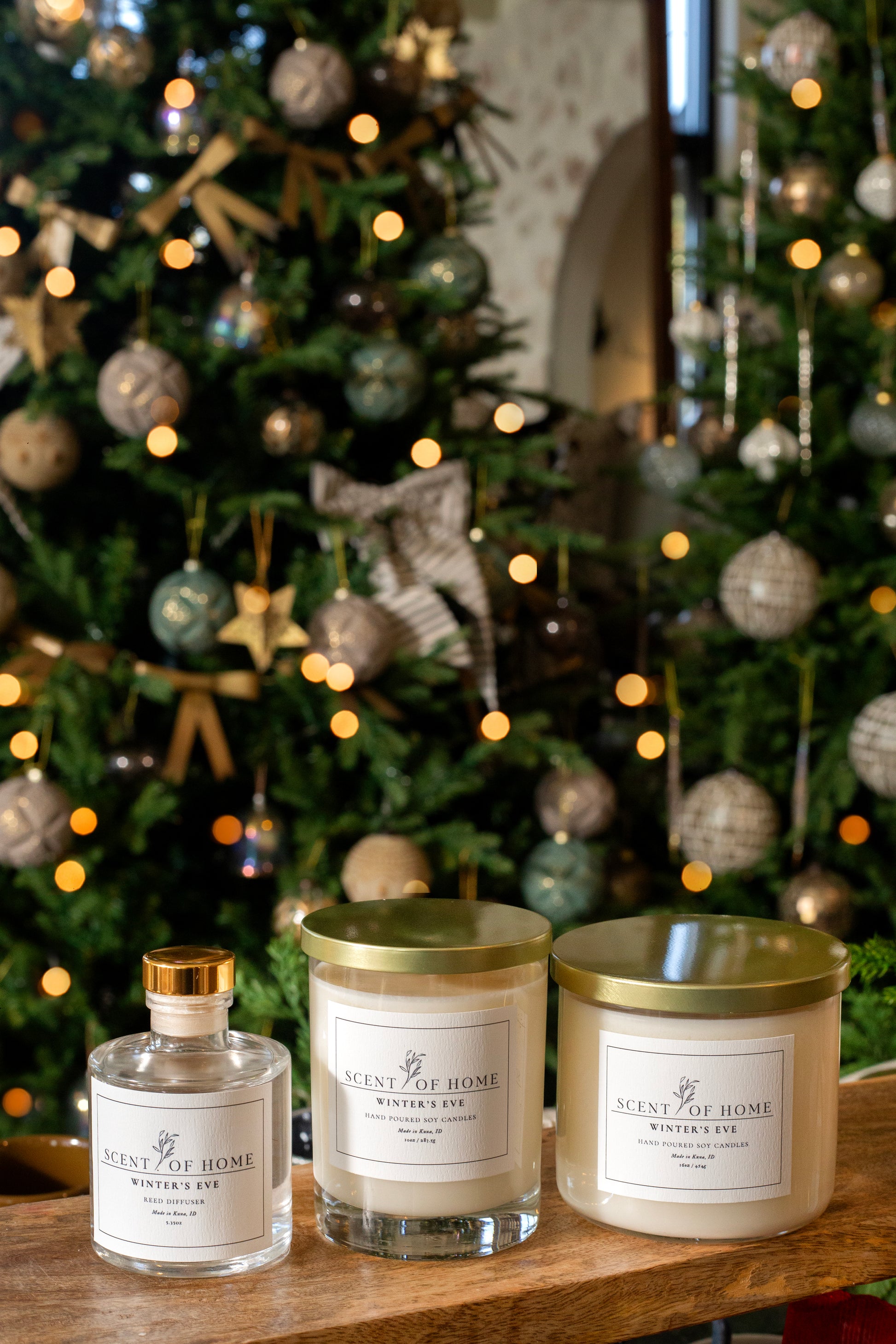 Scent of Home Winter’s Eve holiday bundle featuring a reed diffuser, classic candle, and 3-wick candle displayed in front of a decorated Christmas tree